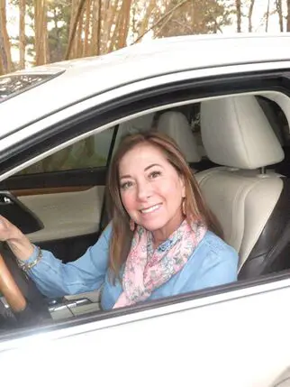 A woman sitting in the driver 's seat of her car.