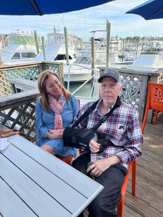 A man and woman sitting on a bench at the dock.